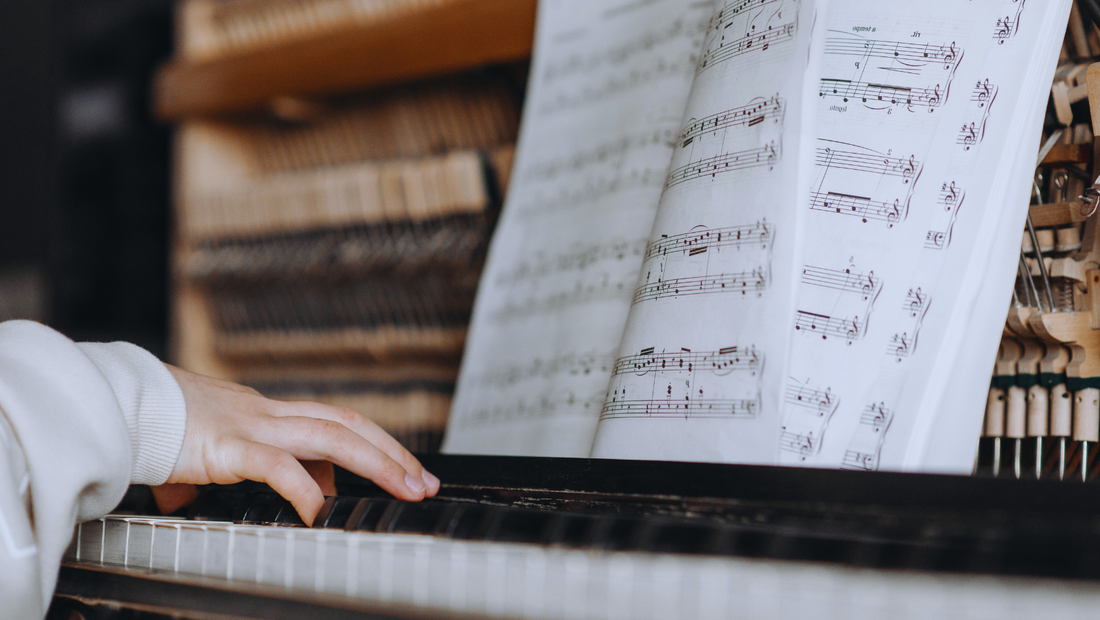 Person playing piano while reading music notes