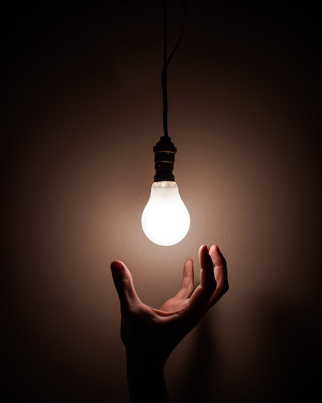 Hand reaching for light bulb that is on