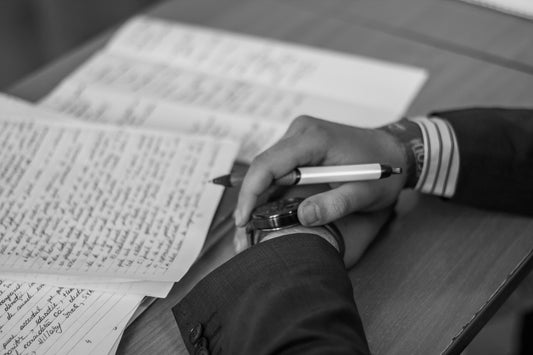 grayscale-photography-of-person-holding-pen