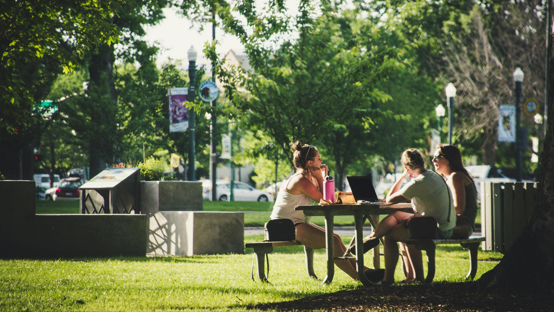 three persons in a park sitting around a table