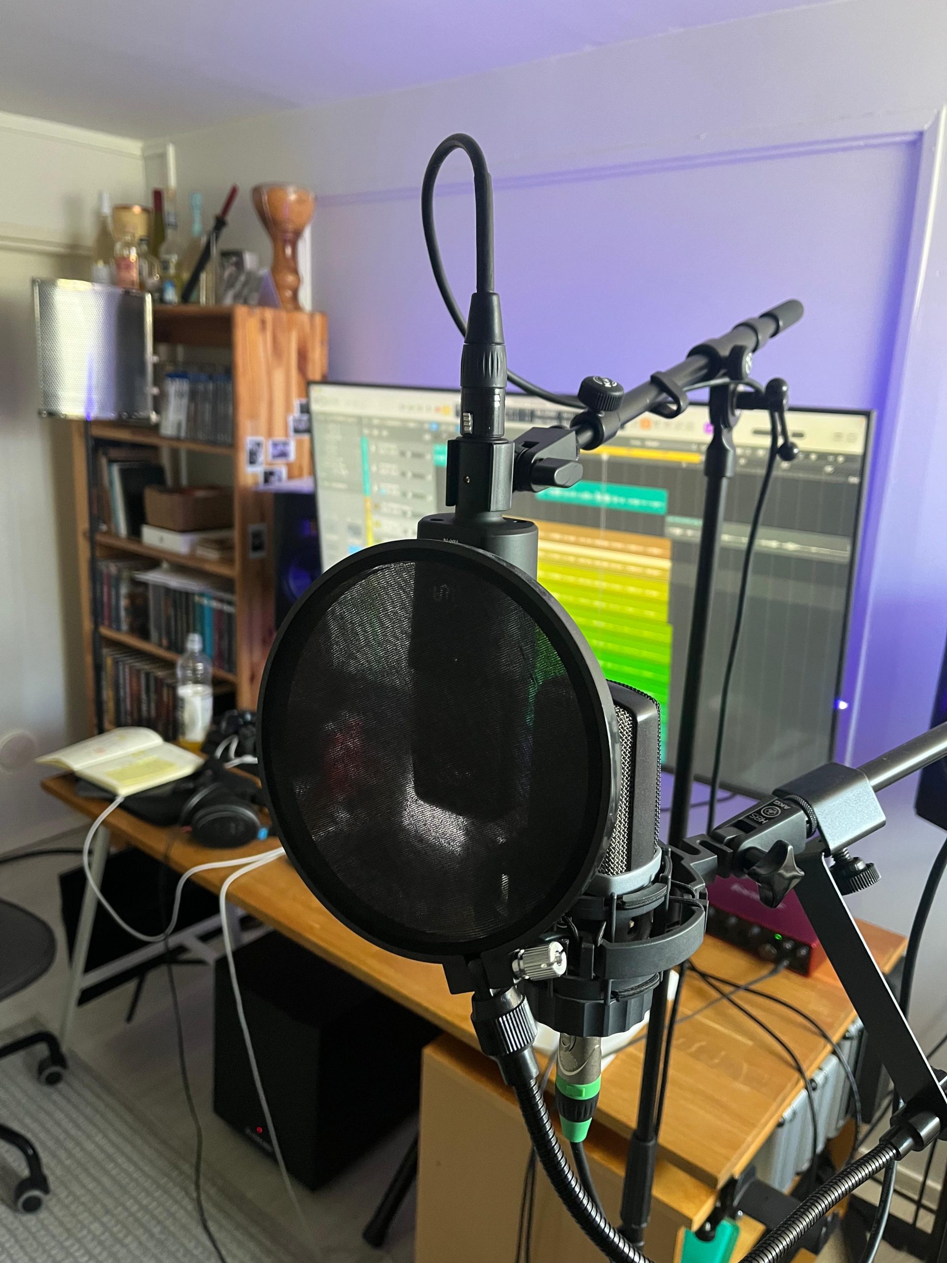 mikrofoni ja suoja sen edessä. takana tietokone jossa musiikinteko-ohjelma